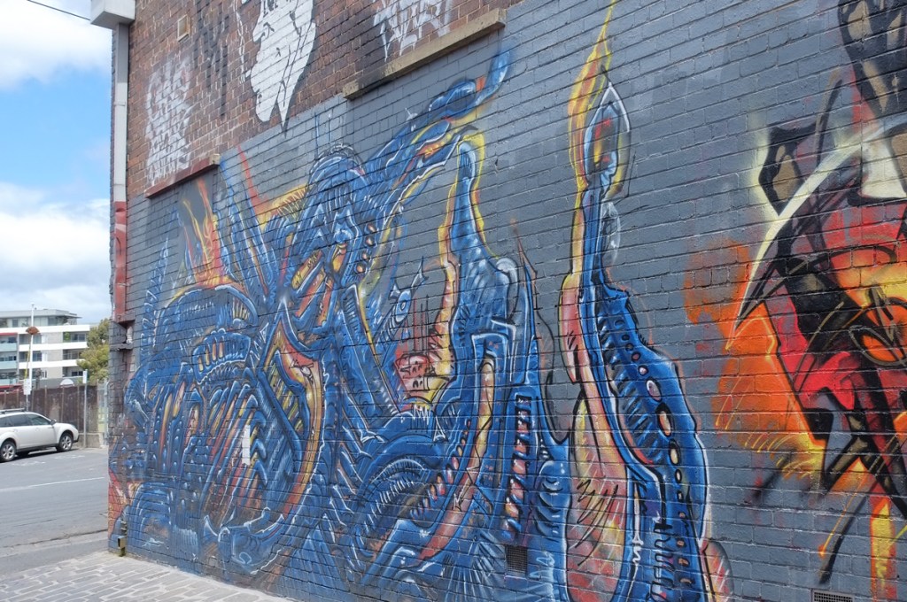 a blue mural at the end of Artist Lane, a blue creature