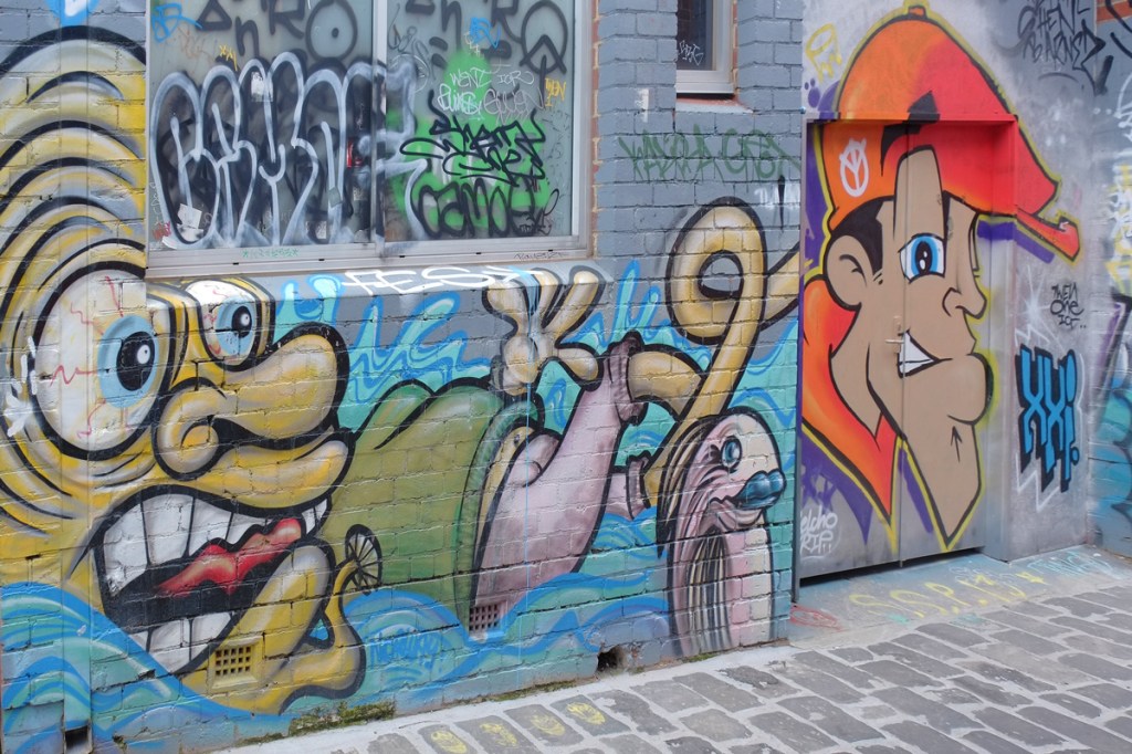 street art in Artist Lane, two faces, one man in orange hat, also a fish