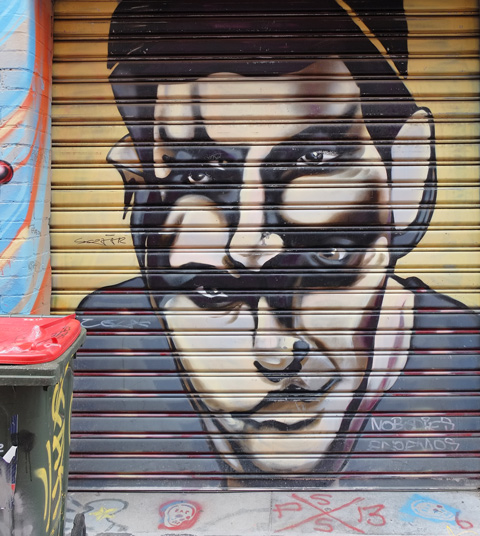street art painting in Artist Lane of a man with two merged heads.  He has one set of hair, four eyes, two noses, one mouth. 