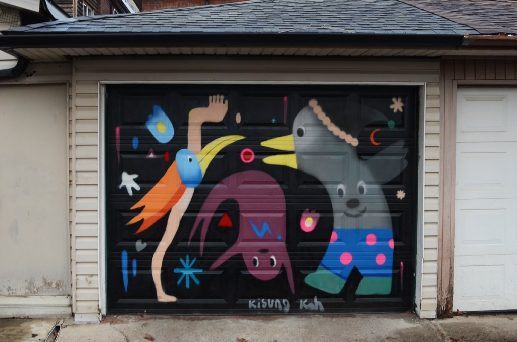 mural by Kisong Koh on the door of a garage in a laneway of three nonsensical fantasy creatures, a purple animal with fins for legs is upside down, a grey creature is wearing blue boxer shorts with pink polka dots and the third has a long yellow beak, one human hand and foot, and long orange hair