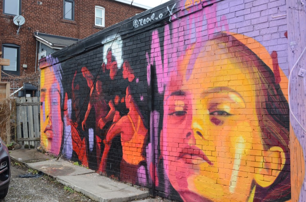 orange and pink woman's head by Anya Mielniczek along with a picture of a group of people, mostly men, by Raoul