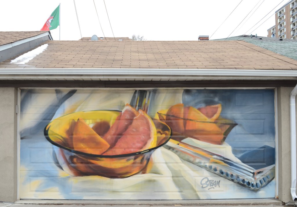 Steam, the artist, painted a mural on a garage door of citrus fruit sections in glass bowls