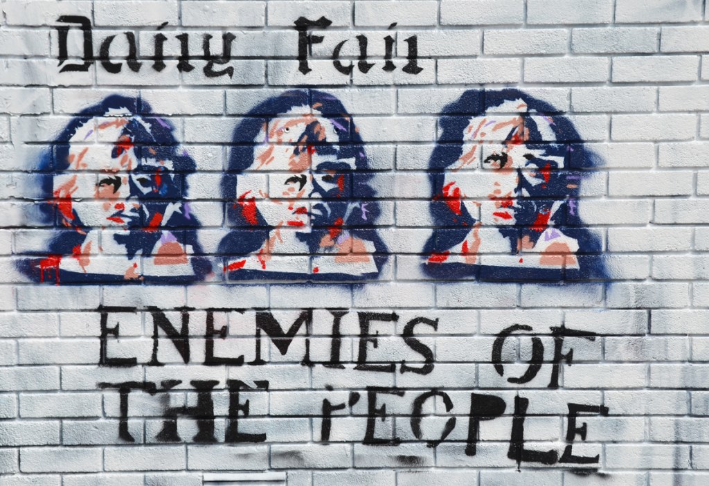 In paradoy of newspaper Daily Mail, text on graffiti says Daily Fail, with three stencil faces