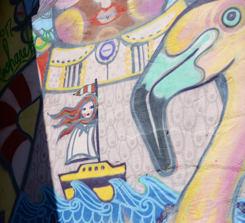 close up of a mural showing a woman in a sail boat, with a large bird and its beak beside