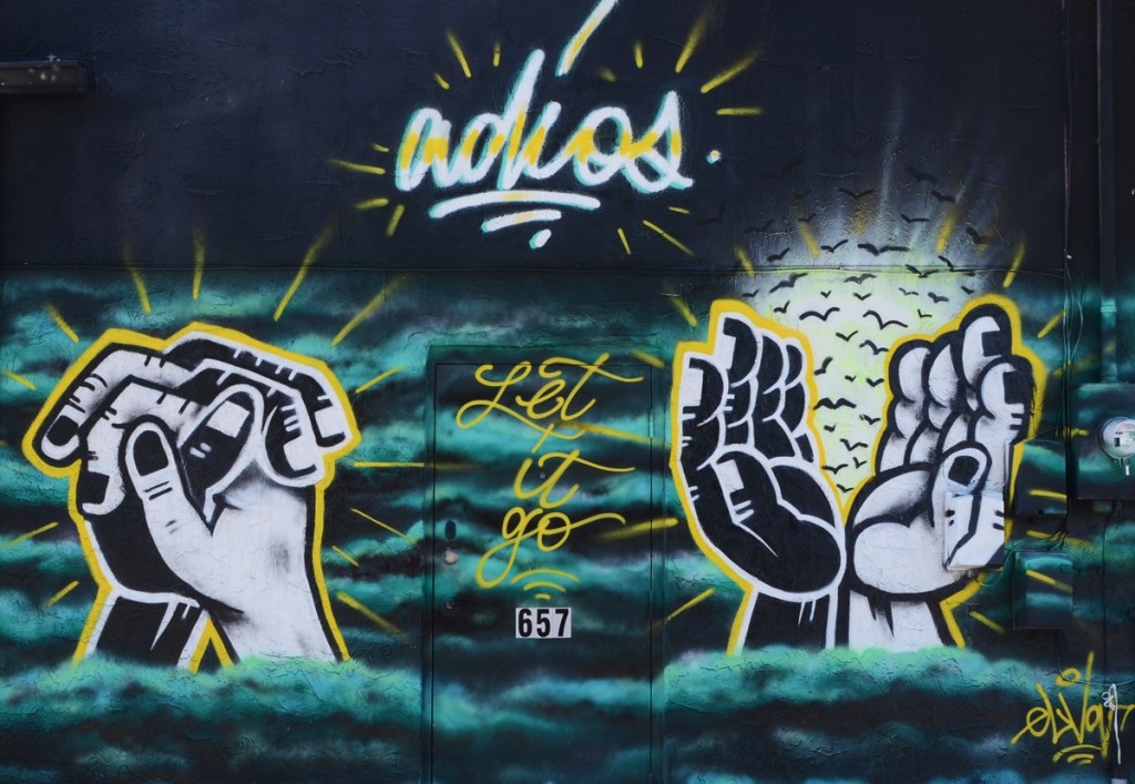 black mural with hands and the word adios in cursive