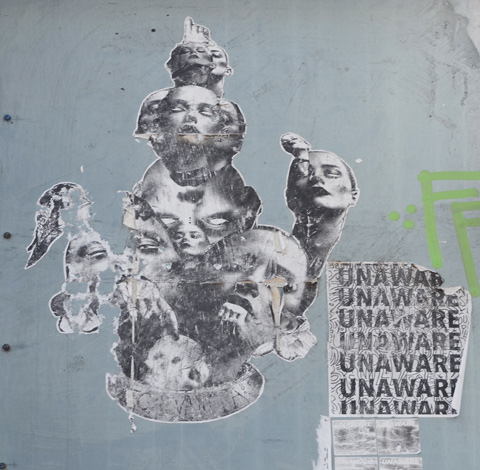 paper paste ups on a wall in a lane