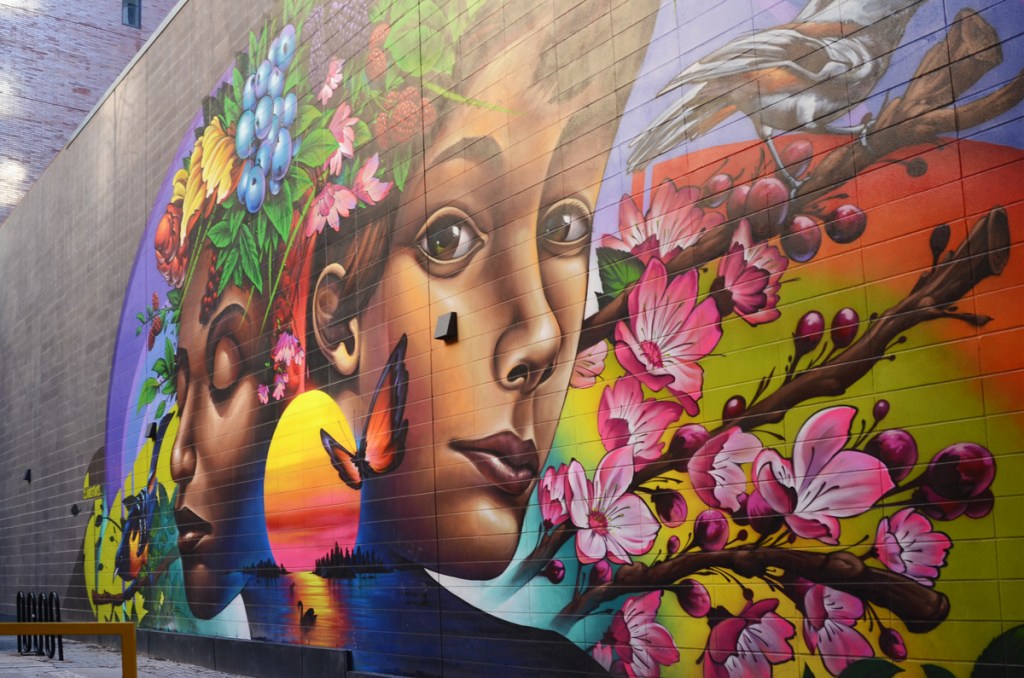 cherry blossoms, faces, painted in a mural, fruit and flowers for hair, raspberries, blackberries, and blueberries