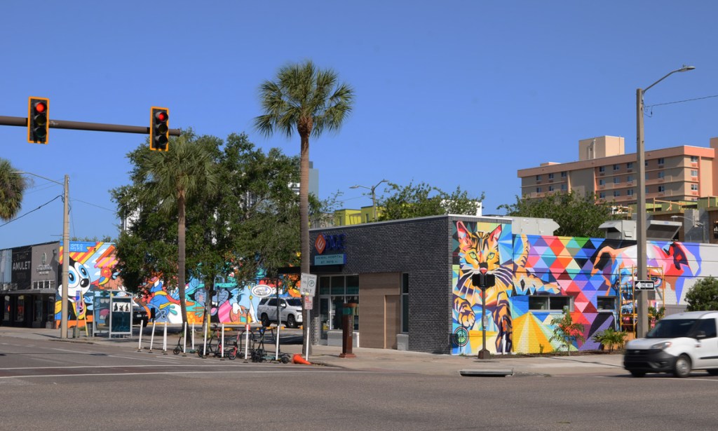 northwest corner of 1st Street North and Martin Luther King Blvd showing some one storey buildings with murals on the sides