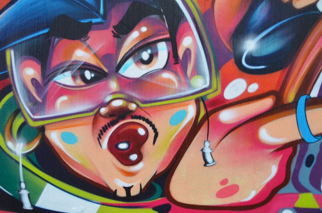 part of a mural, heavy set man with small mustache, wearing a diving, or skiing mask, open mouth,