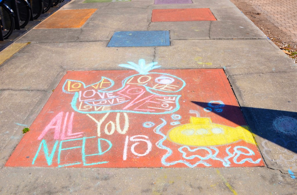 drawing in chalk on the sidewalk, a little yellow submarine and words from Beatles song, all you need is love