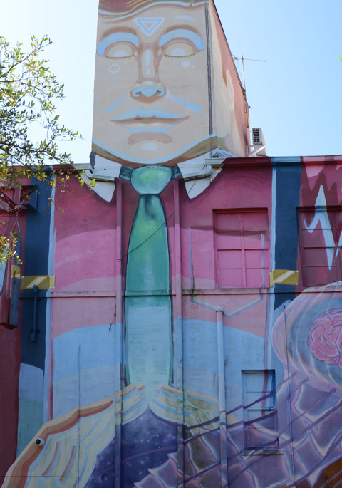 part of a mural, man's hands have created a circular opening in his middle to release a jellyfish with a pink brain