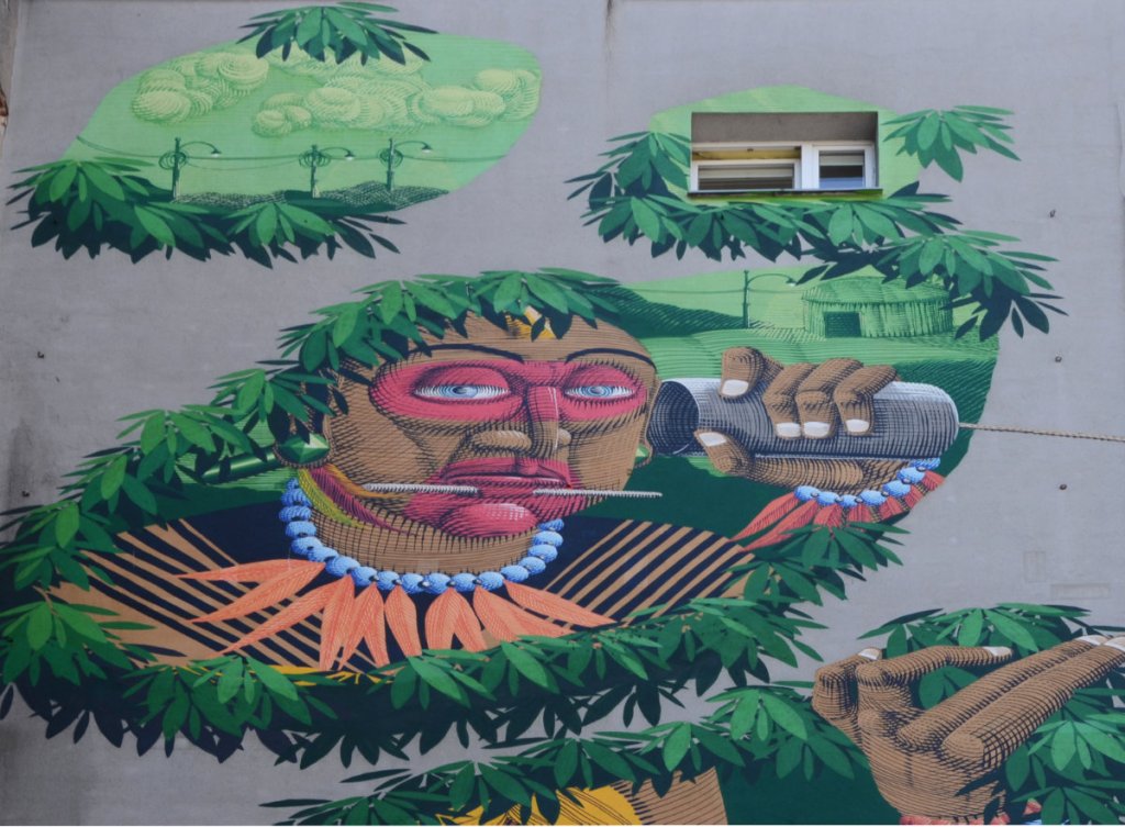 upper part of mural by window of building, Brazilian native man with tin can phone in hand, wearing blue beaded necklace