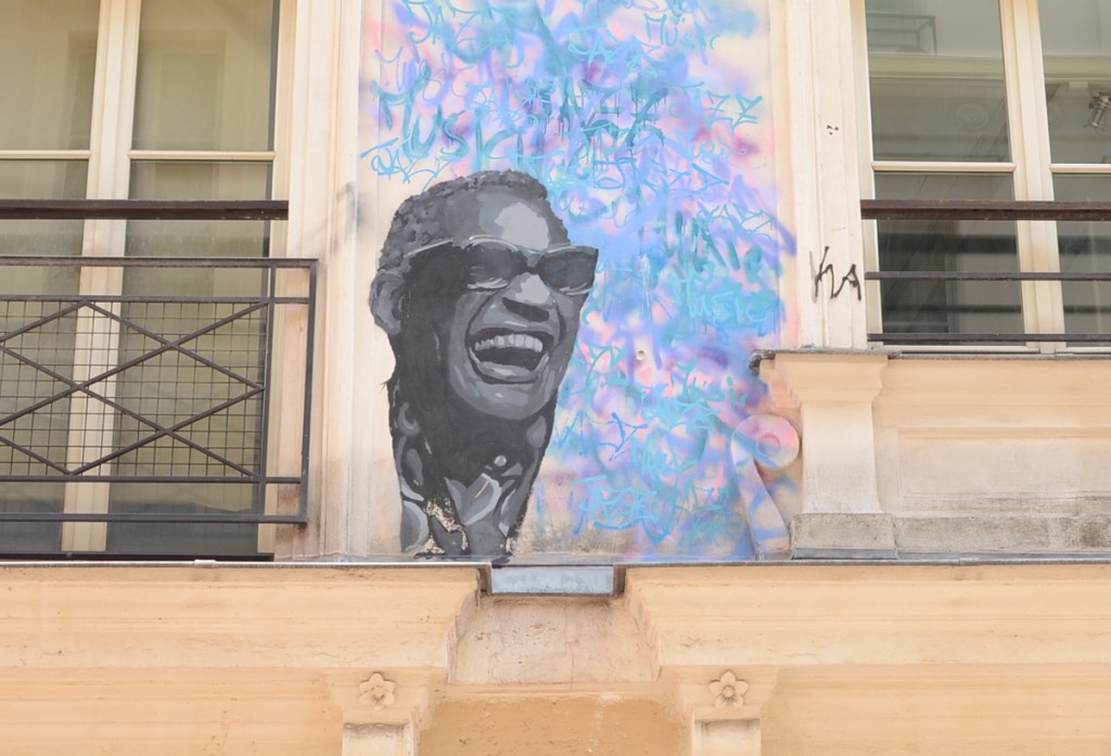 portrait of a man that looks like Stevie Wonder, in grey shades, on blue background, street art, black man with short hair and wearing sunglasses, smiling