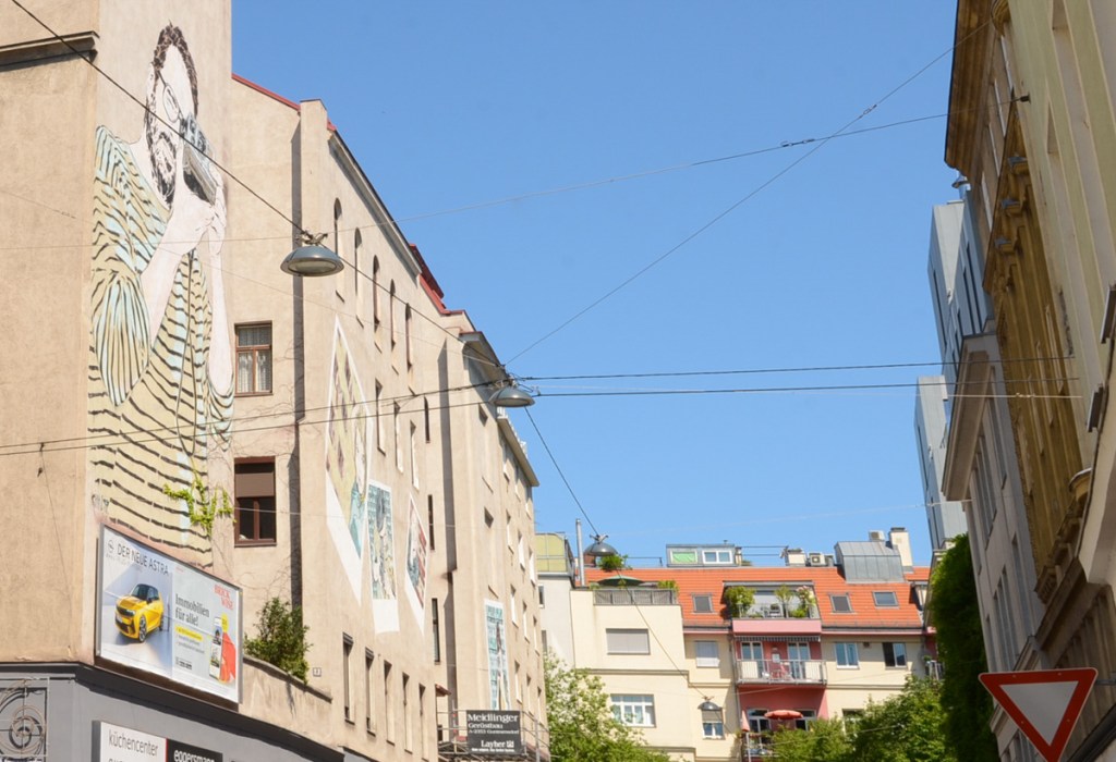 a small dead end street with street art murals on the buildings on the left side