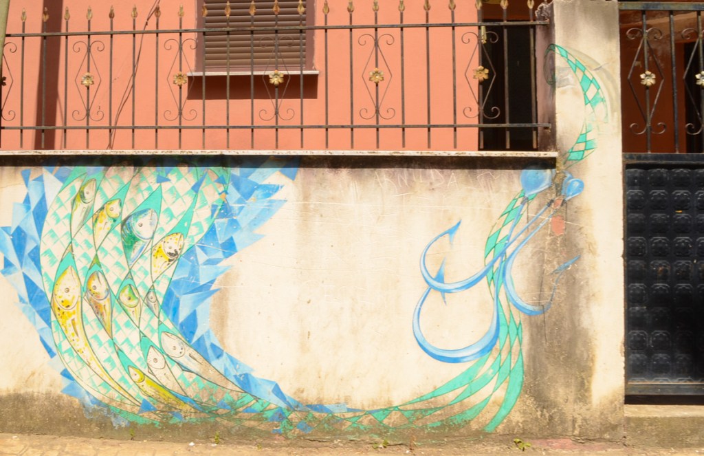 painting of fish swimming away from fish hooks, outdoor mural street art