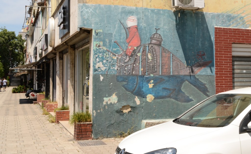 mural of a child riding on the back of a character that is half fish and half submarine