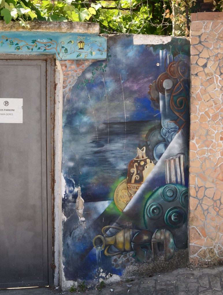 mural on a wall in an alley, seaside, old urn or jug, a helmet, other treasures washed up on the shore or hidden away