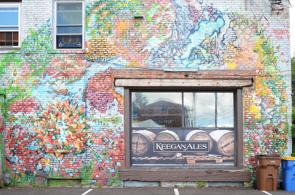 mural on an exterior of Keegan Ales, with window and reflections in the middle of the picture, mural painted by 