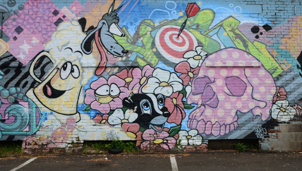mural on Keegan Ale exterior, cartoon like characters and items, skull, skunk, dart board,
