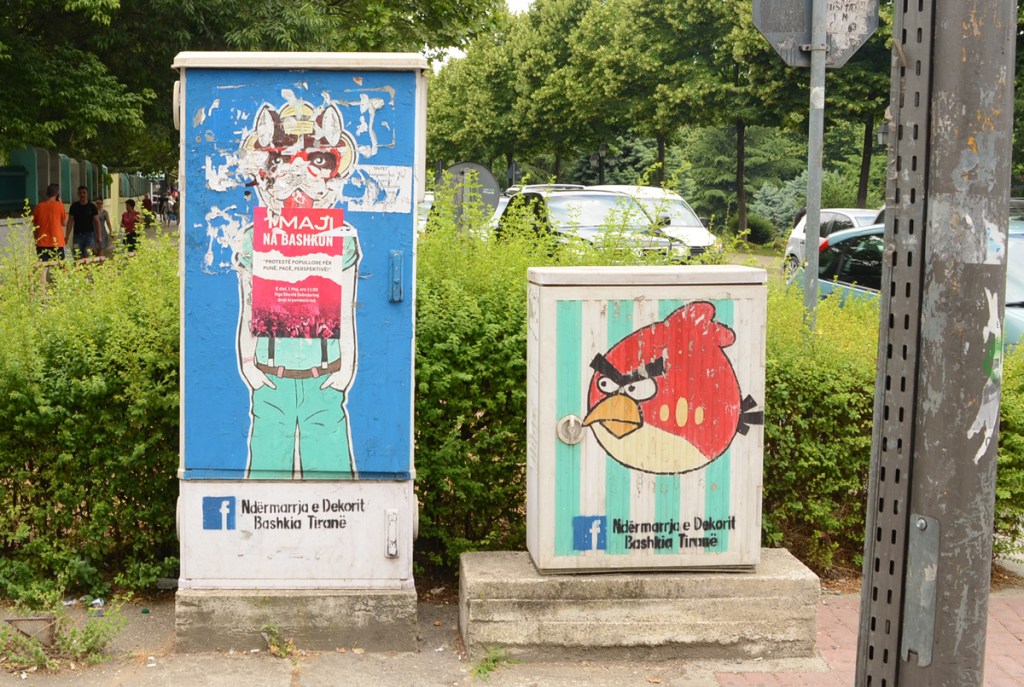 two painted sidewalk box on a sidewalk in Tirana, the one on the right is a red angry bird from the game