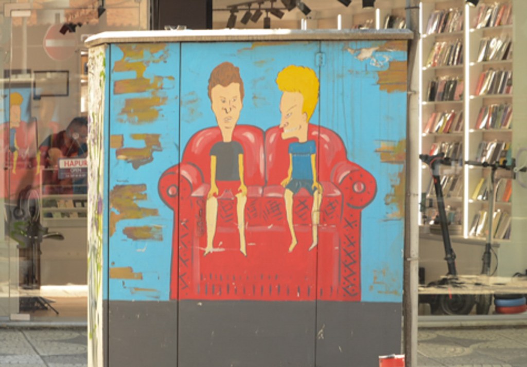 painted sidewalk box on a sidewalk in Tirana, television characters from the 1990s, Beavis and Butthead, sitting on a red couch