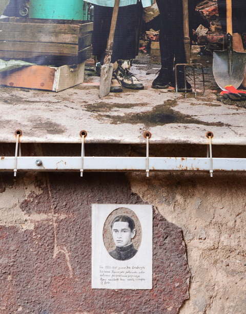 on exterior wall, black and white photo of man, below part of a larger colour photo