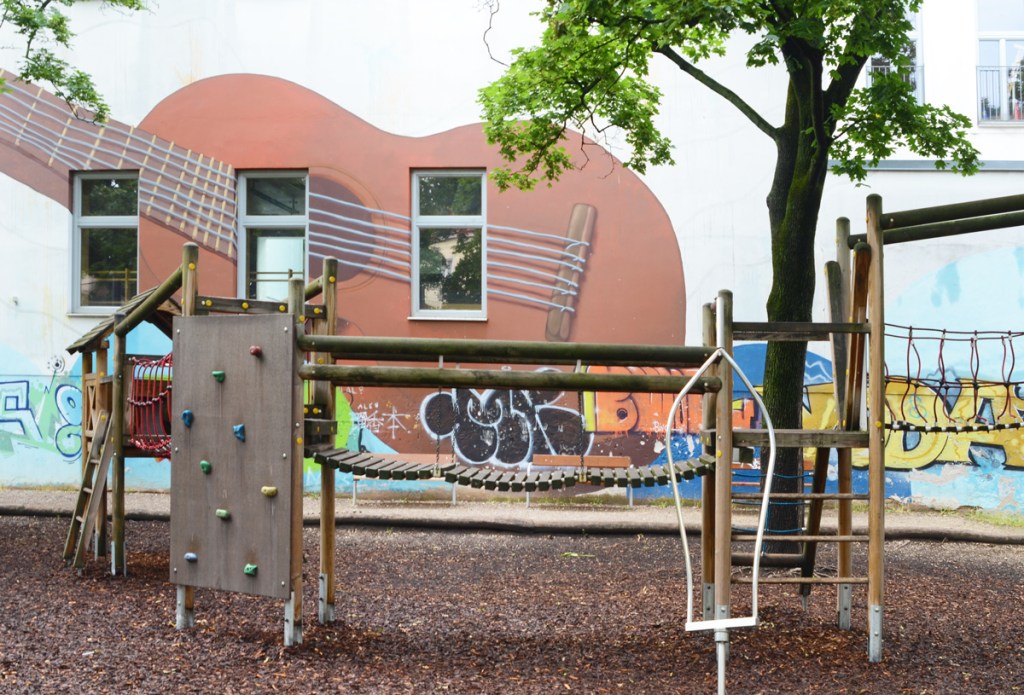 large acoustic guitar in mural on side of school painted by El Jerrino
