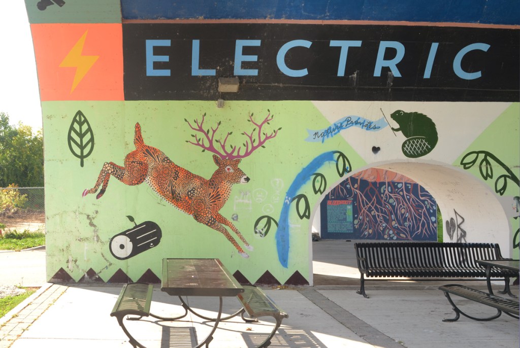 arch under a bridge, street art painting of jumping deer with magenta antlers, a beaver, a log, and some leaves, 