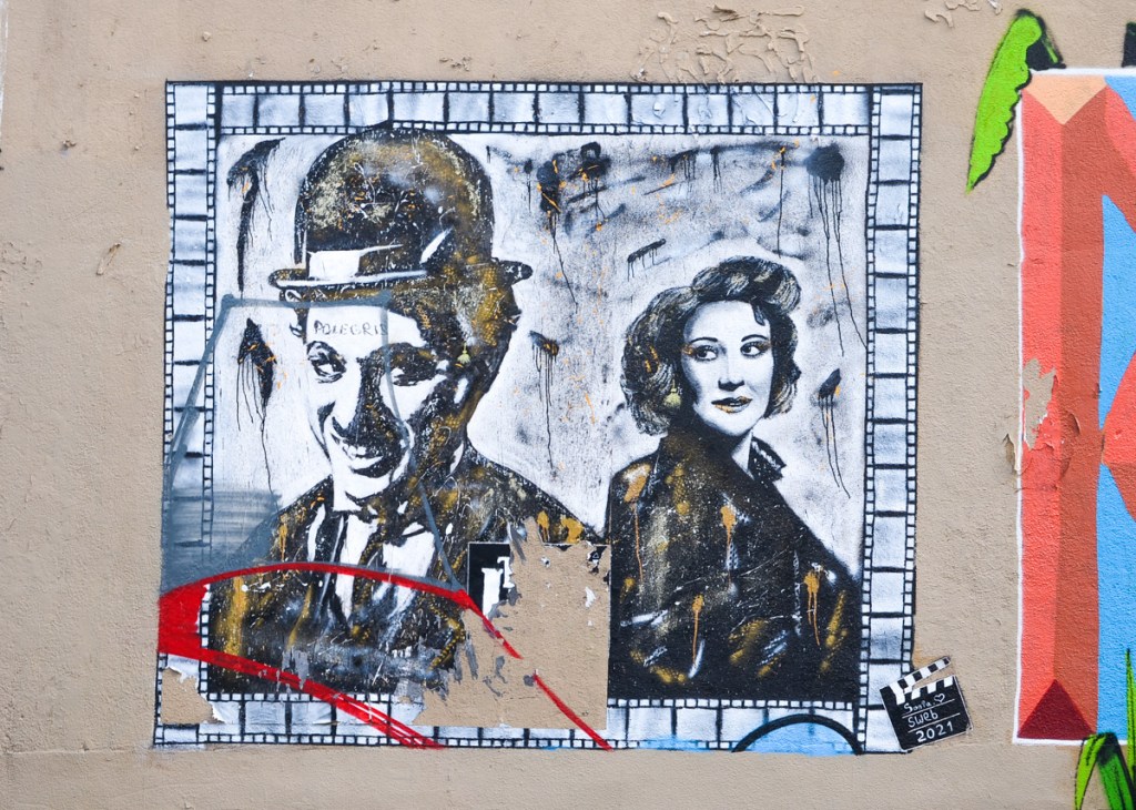 black and white street art painting, portrait of Charlie Chaplin, also a female actress, border is film with sprocket holes