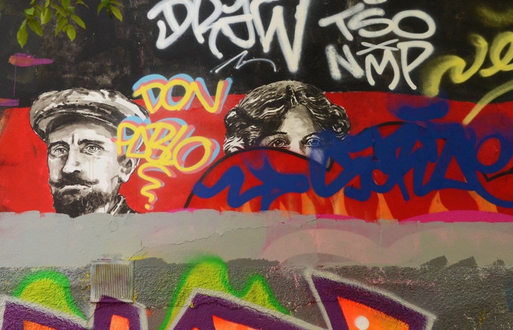 two faces, a man and a woman, in black and white remain while the rest of their mural has been covered over by another