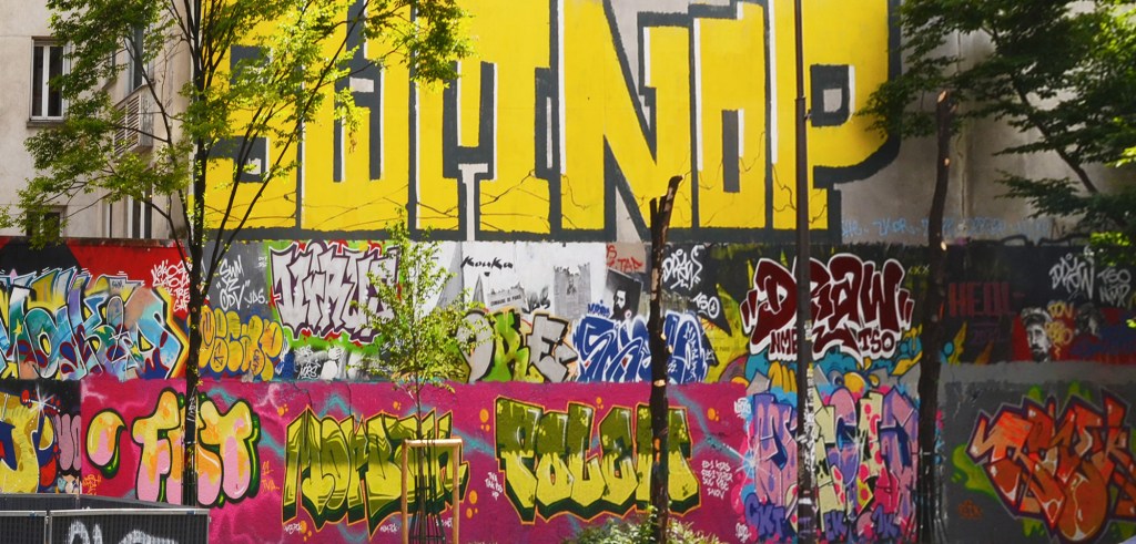 a wall of throw up street art, different tags in different colours and styles