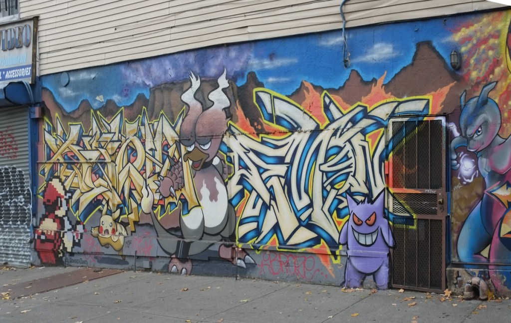 part of poke wall mural in bushwick showing some pokemon characters such as gengar who is purple, some yellow text tag graffiti in the mural too