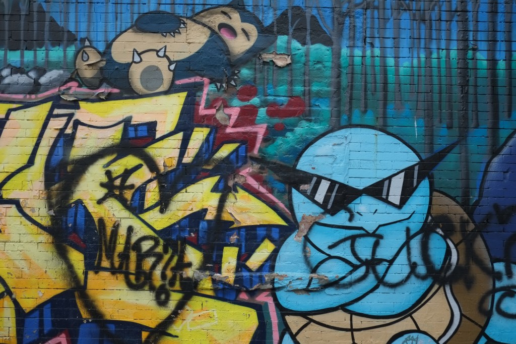 poke wall mural with pokemon characters including a snorlax who is sleeping on top of some text