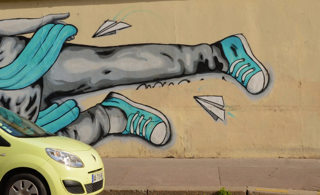 yellow car parked in front of a mural, close up of legs with blue running shoes