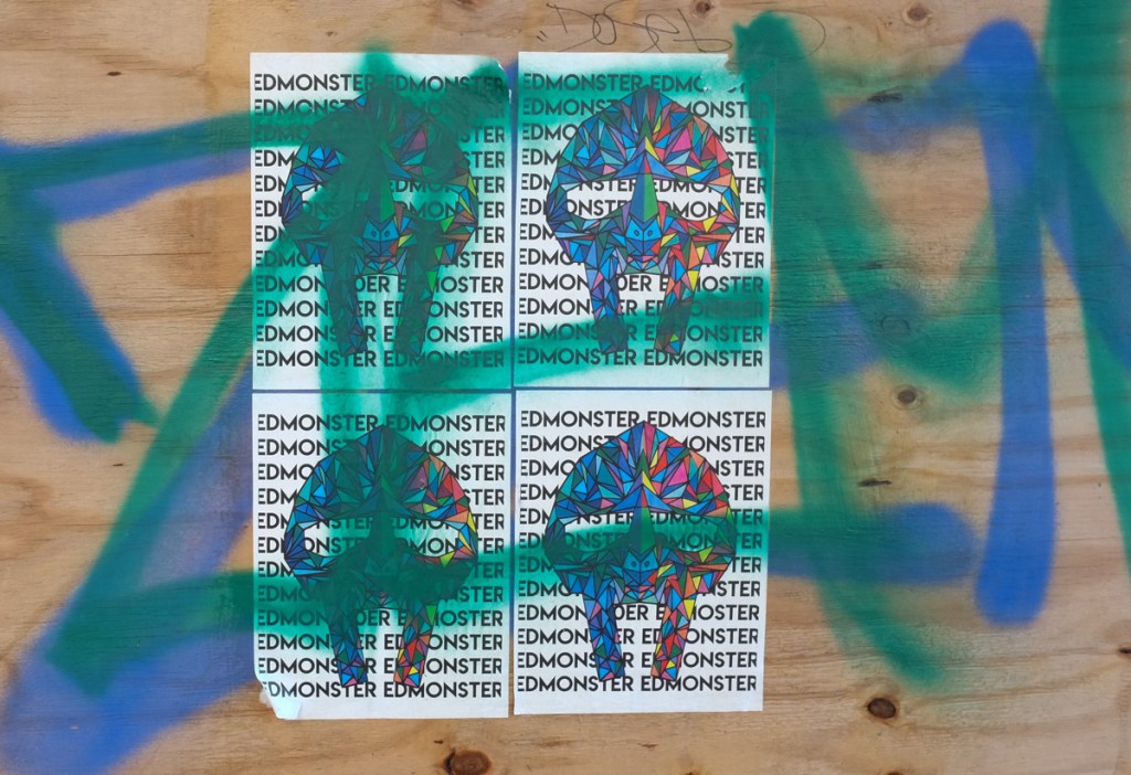 graffiti on the side of a box on the street, edmonster, four identical pictures of a multicoloured monster