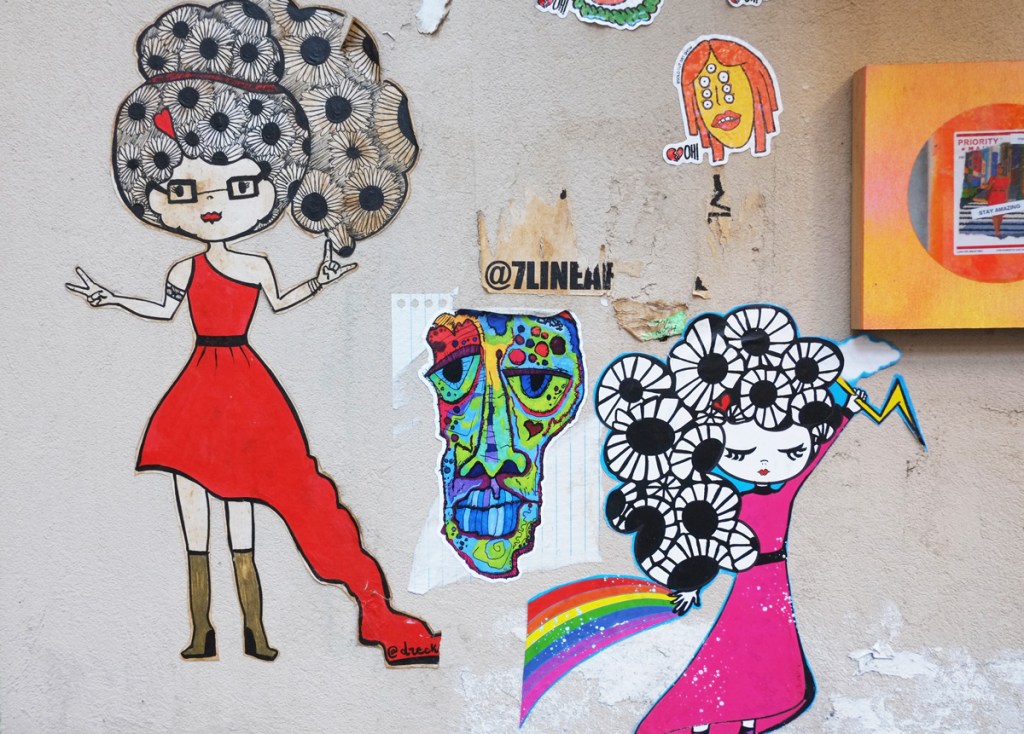 drecks drawing of a female character with hair as big black and white flowers, slaps in new york city, two side by side, one in a red dress and the other in a pink dress