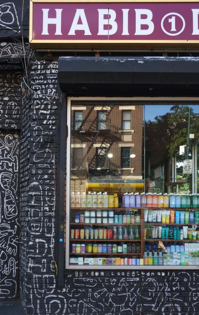 store window with word habib, in the middle of a mural that is white drawings on black background