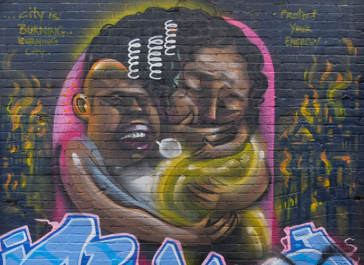 a painting on the side of a wall on Croft Ave., by elicser elliott, of two people with text protect your energy