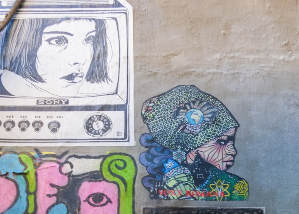 two wheatpaste, one is black and white image of an old sony television with a woman's head on the screen, the other is a piece by voxx romana for black lives matter, also a woman's profile