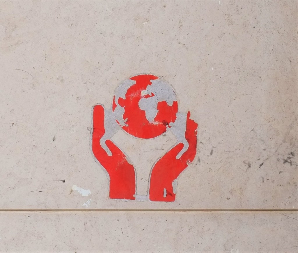 graffiti, red on white, a globe of the Earth being held by two hands