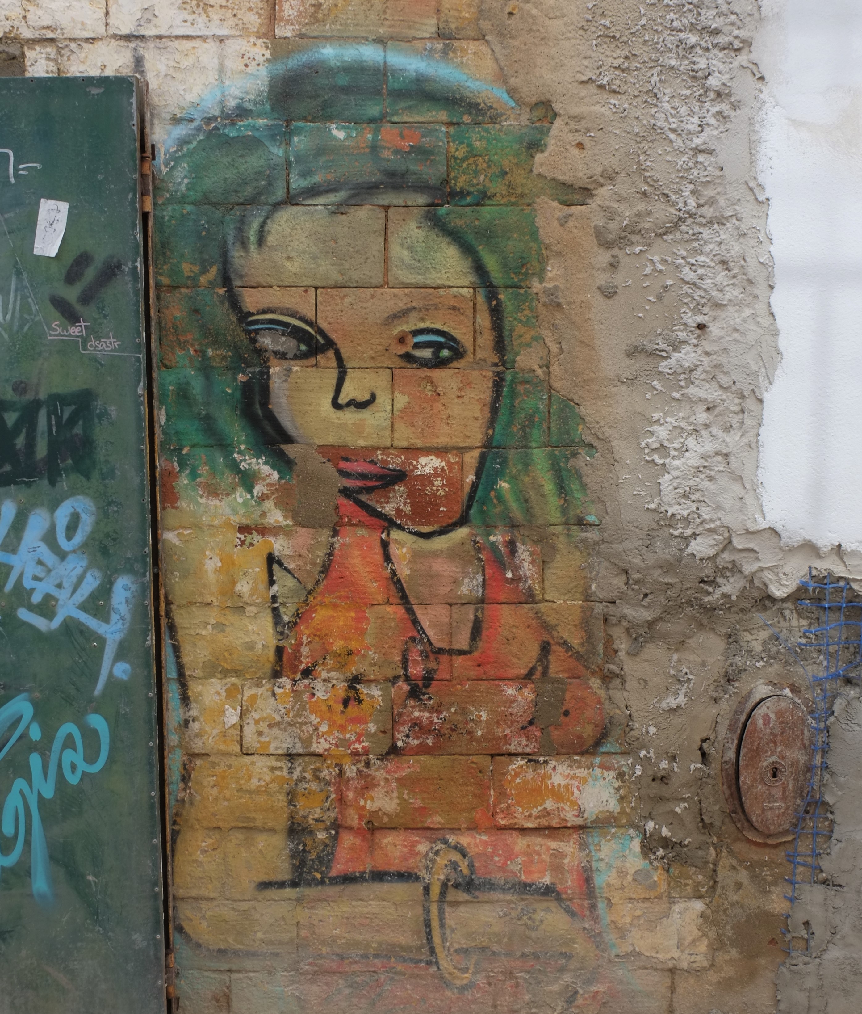 street art painting of a woman with greenish blue hair, blue eye shadow and red lips