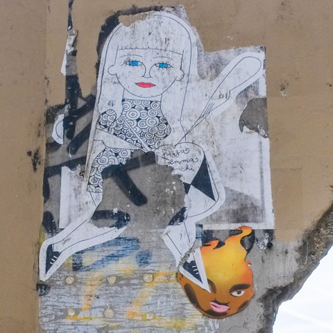 torn wheatpaste, a drawing of a young woman with bright blue eyes and red lipstick and small pointy feet, her top is covered with circles