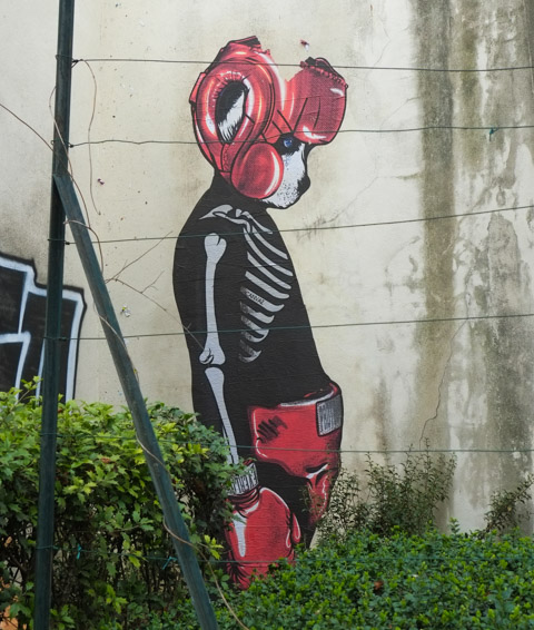 street art by canvaz, large size boxer with dog face, a tear in his eye, with ear protection, boxing shorts, and boxing  gloves, on a wall