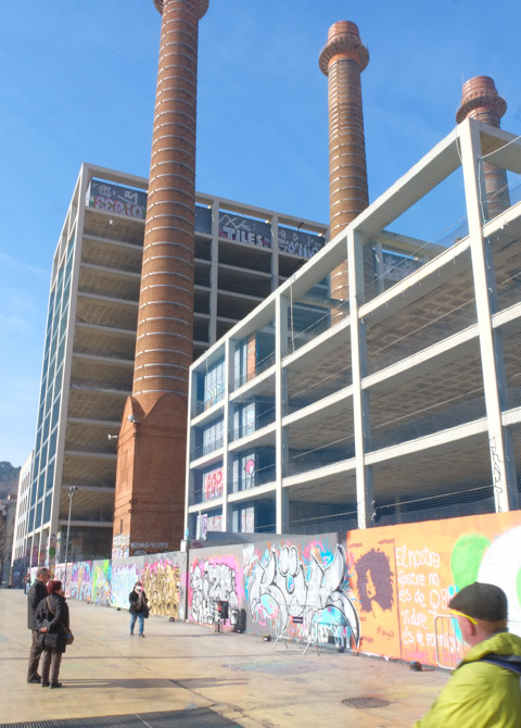 three tall brick chimneys remaining from old coal burning power plant, now part of an urban park with street art on the walls