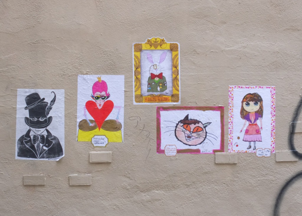 5 posters on an outside wall, each with a painting on it
