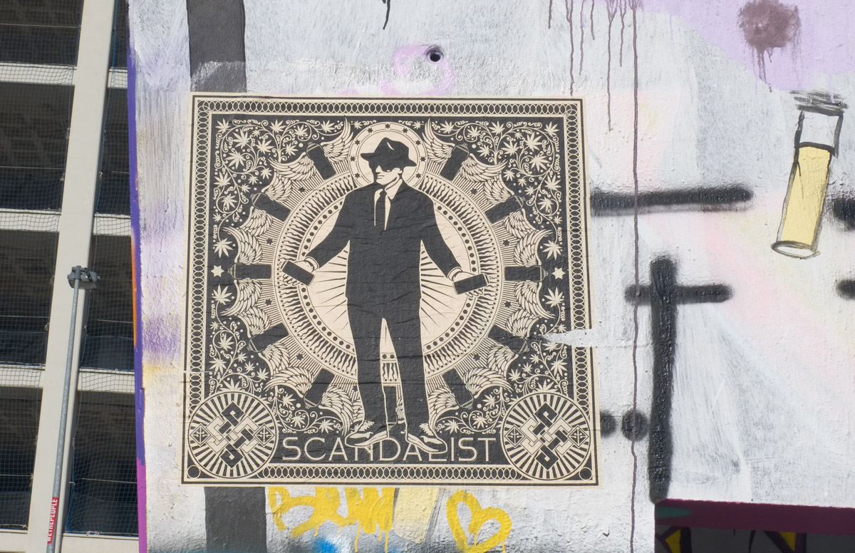 scandalist   wheatpaste graffiti, picture of a man in suit, dark sunglasses, and hat