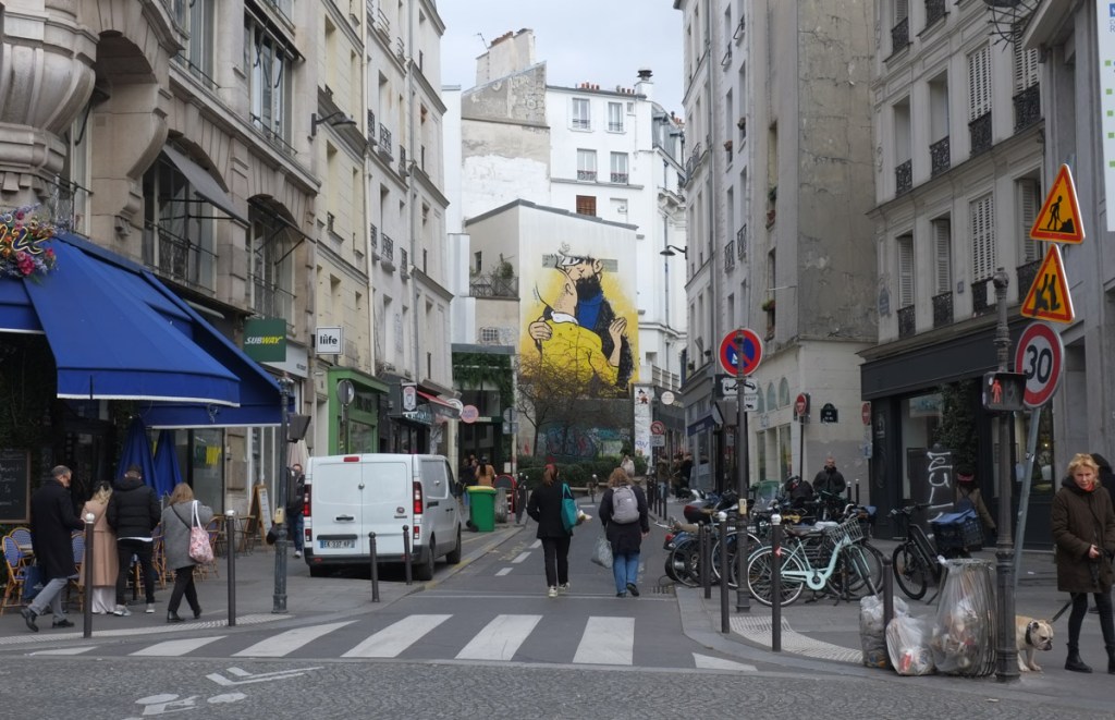 looking up a short Paris street with a mural of Tintin in a yellow shirt at the end of the street