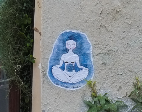 wheatpaste graffiti in blue tones by wild wonder woman, naked women in yoga pose with night sky behind