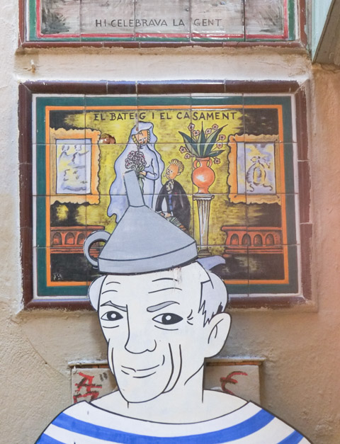 top part of a large cutout of a man with a blue and white striped shirt and a grey funnel upside down on his head, he stands in front of a small wall with two ceramic plaques on them.  the lower picture is of a bride and a groom. 