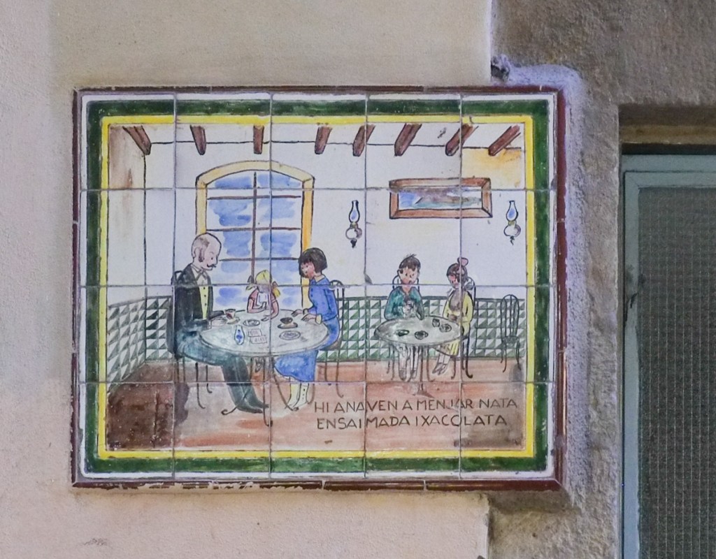 ceramic plaque on concrete wall, picture, interior of a restaurant with two round tables, people sitting at tables with cups of chocolate 